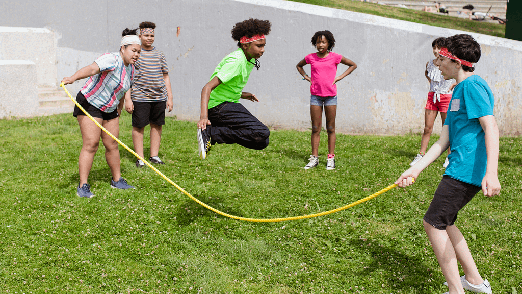 School-aged children performing resistance training exercises, such as push-ups and squats, in a gym setting. The image emphasizes physical strength, health, and fitness development.