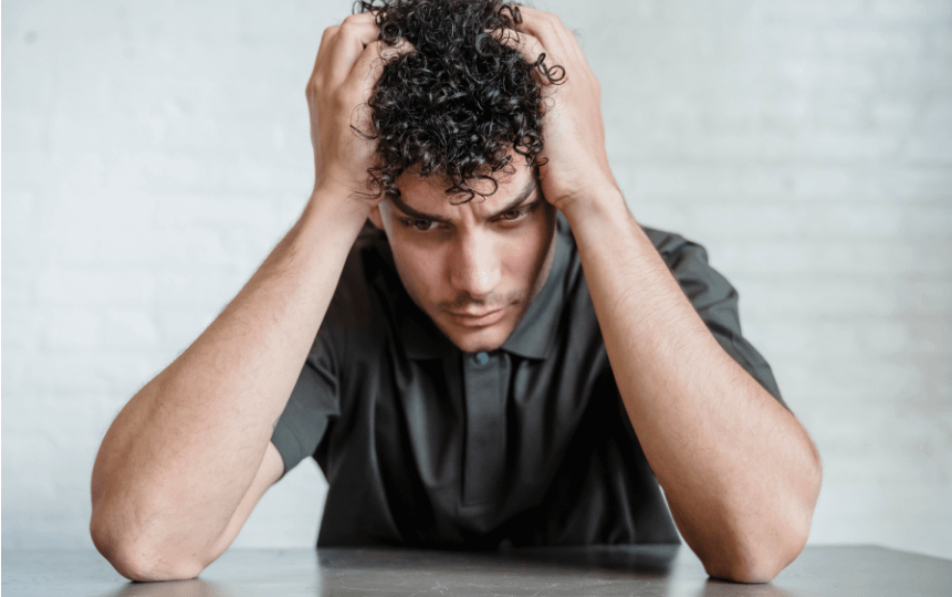 A Brazilian Jiu-Jitsu student, looking thoughtful and stressed. The student appears deep in thought, reflecting the emotional pressure of meeting new expectations.