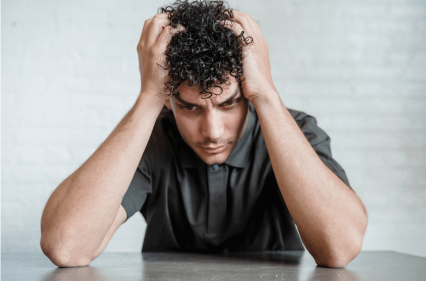 A Brazilian Jiu-Jitsu student, looking thoughtful and stressed. The student appears deep in thought, reflecting the emotional pressure of meeting new expectations.